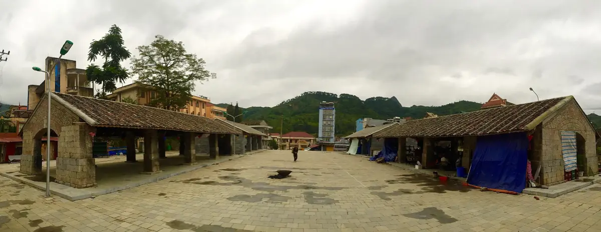 Alte Marktgebäude und offener Platz in Dong Van mit Hügeln im Hintergrund
