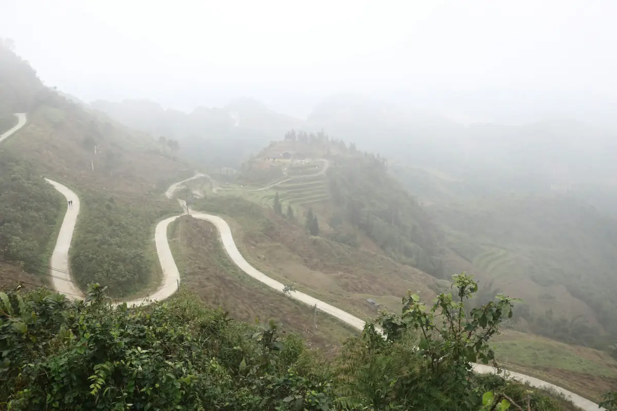 Serpentinen einer Bergstraße, die aus dem Nebel auftauchen, in Ha Giang