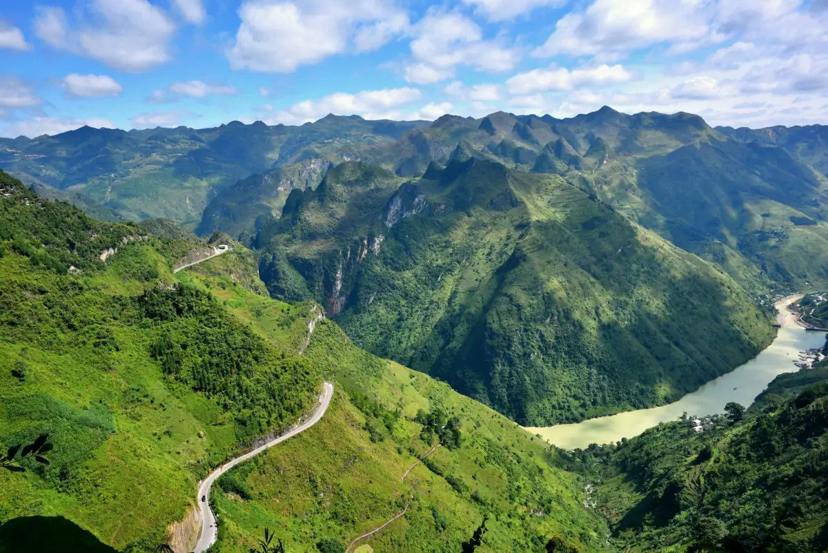 Bergstraße über einer Flussschlucht unter blauem Himmel in Ha Giang